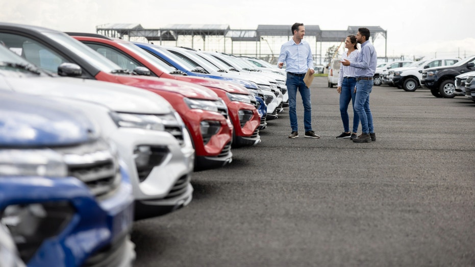 A couple talks with a car dealer after they purchased a new vehicle.
